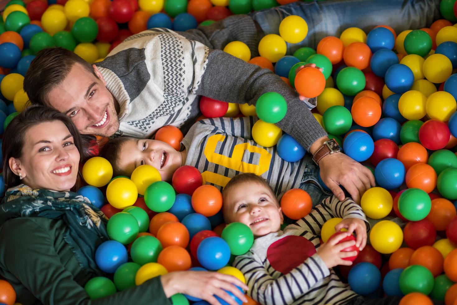 parents and kids playing in the pool with colorful balls photo