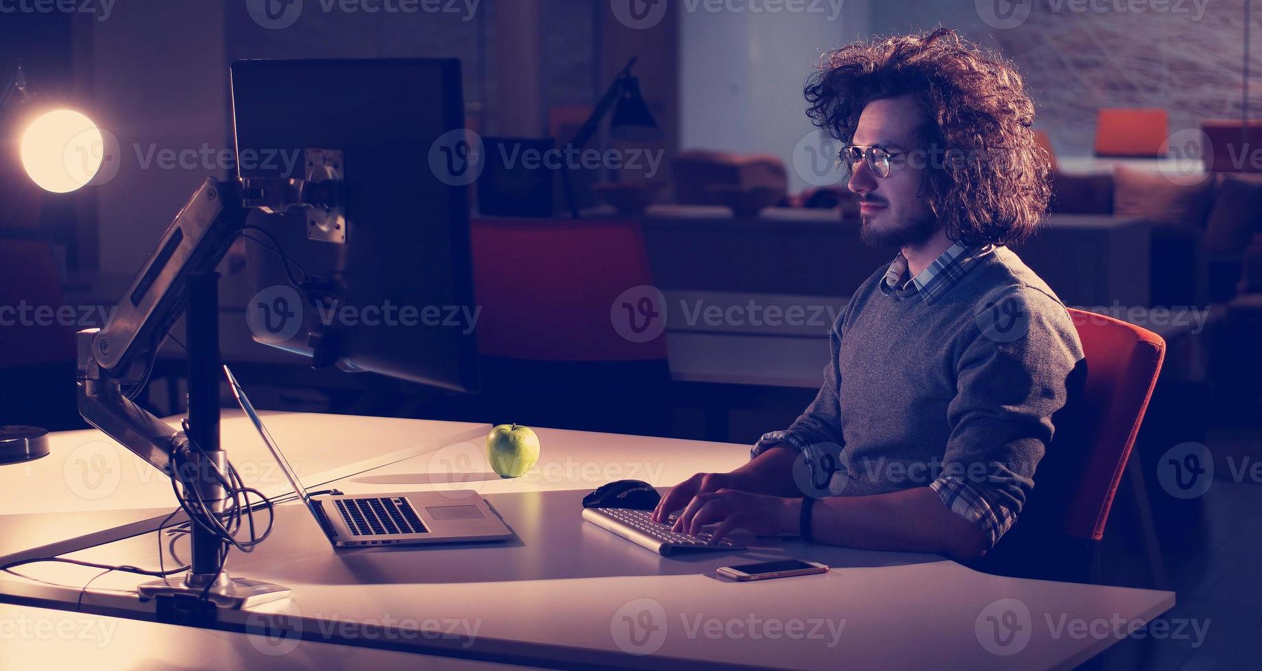 man working on computer in dark office photo