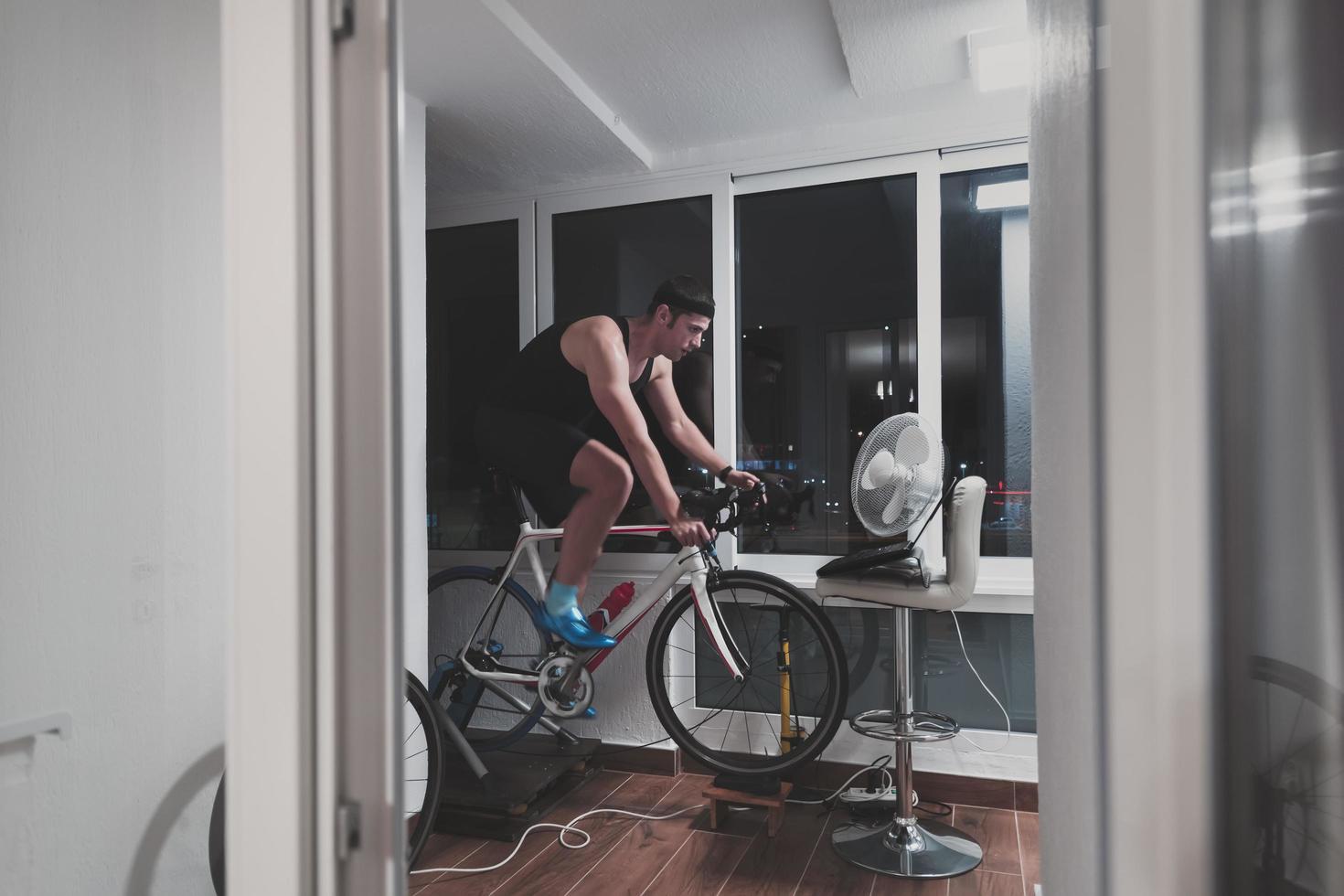 Man cycling on the machine trainer he is exercising in the home at night playing online bike racing game photo