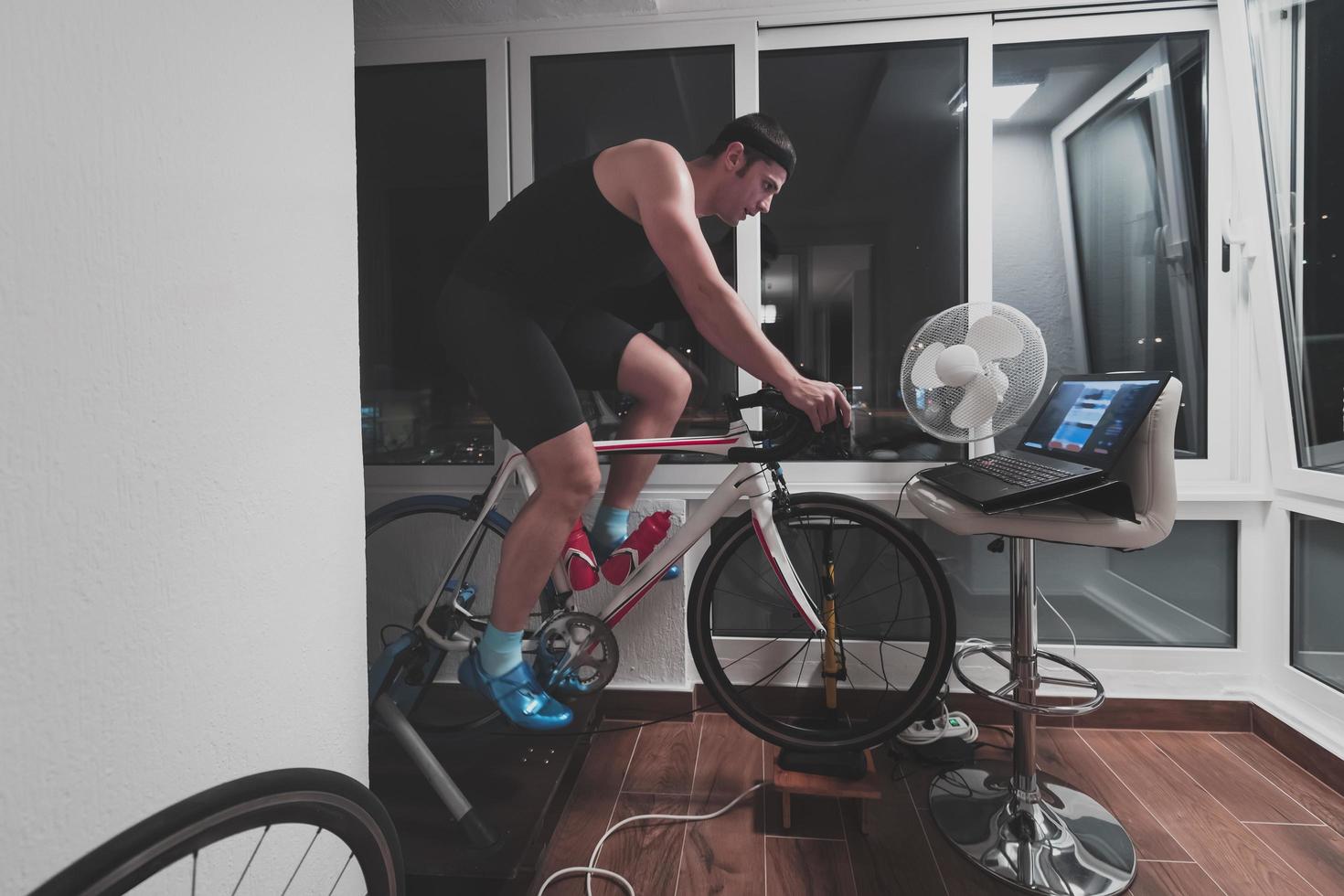 Man cycling on the machine trainer he is exercising in the home at night playing online bike racing game photo