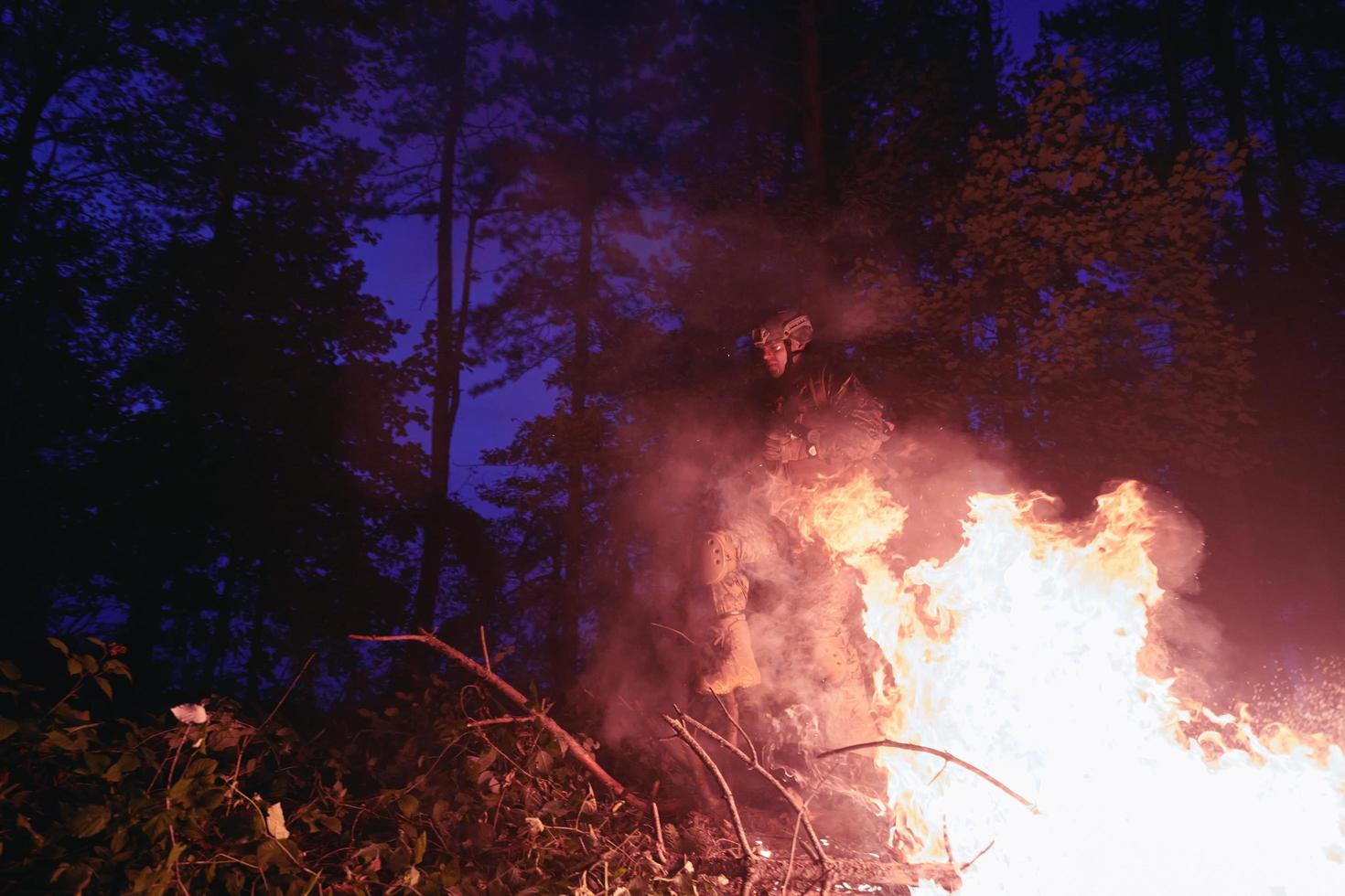 Soldier in Action at Night jumping over fire photo