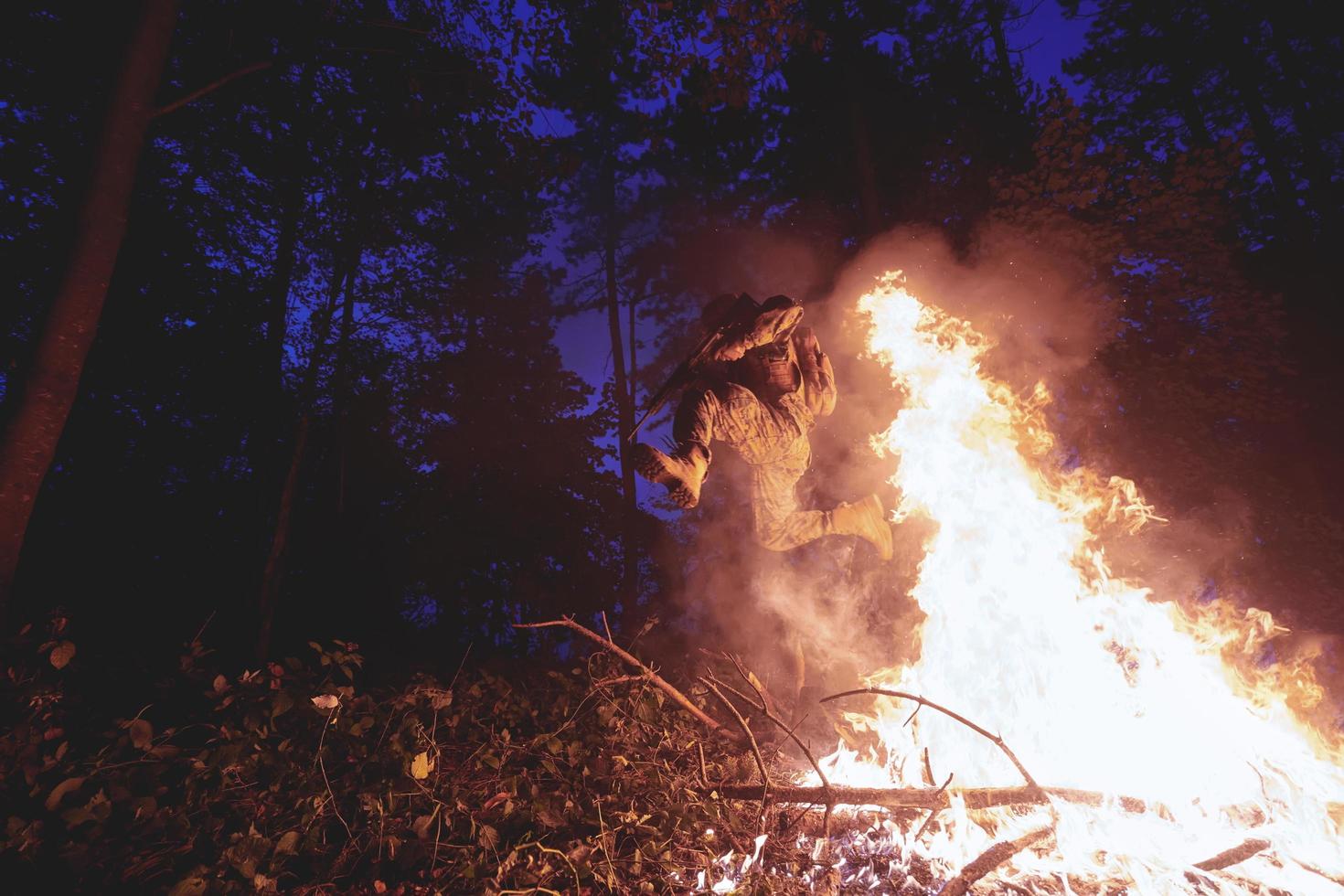 soldado en acción por la noche saltando sobre el fuego foto