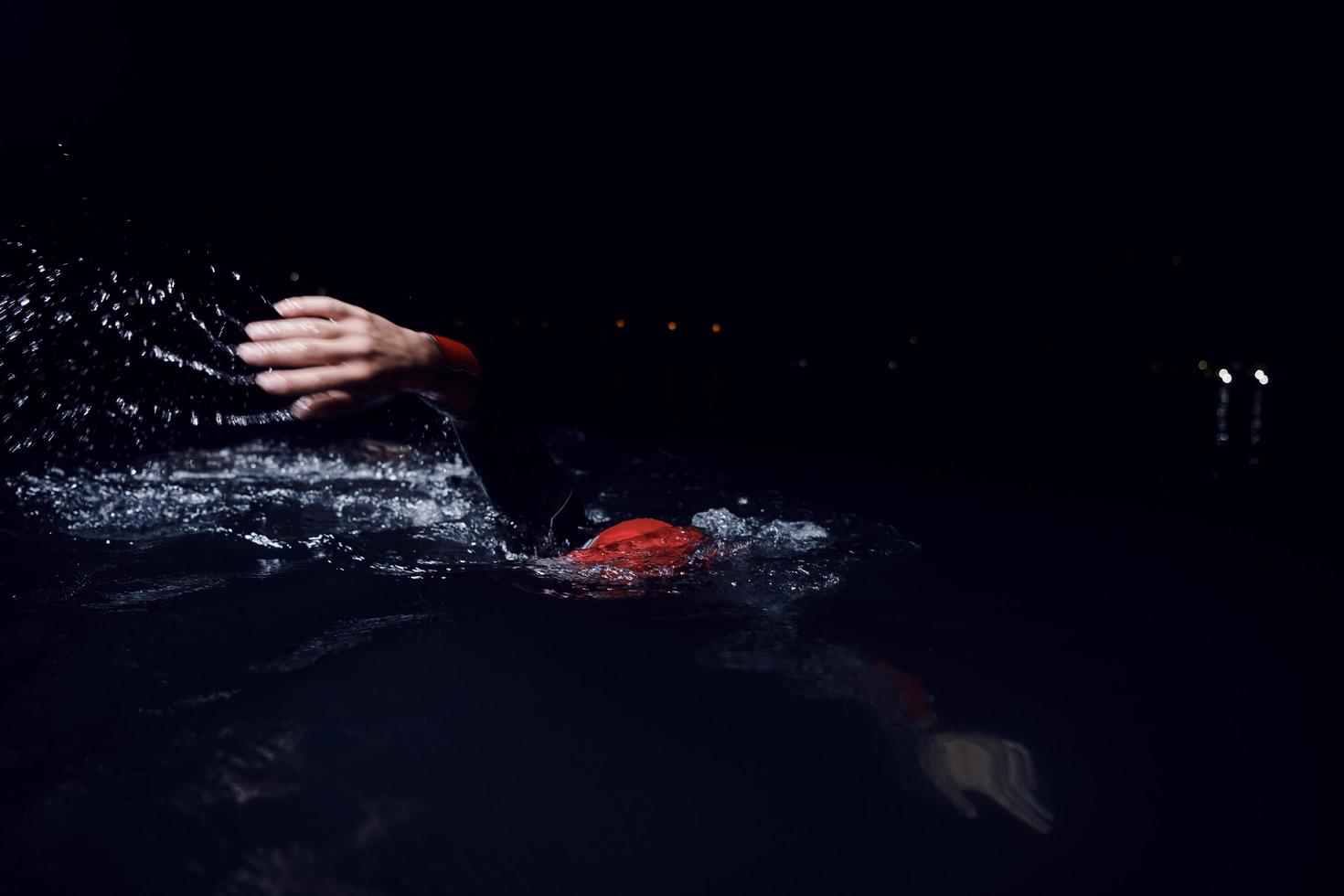 triathlon athlete swimming in dark night  wearing wetsuit photo