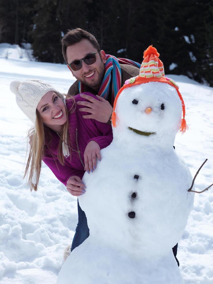 retrato, de, feliz, pareja joven, con, muñeco de nieve foto