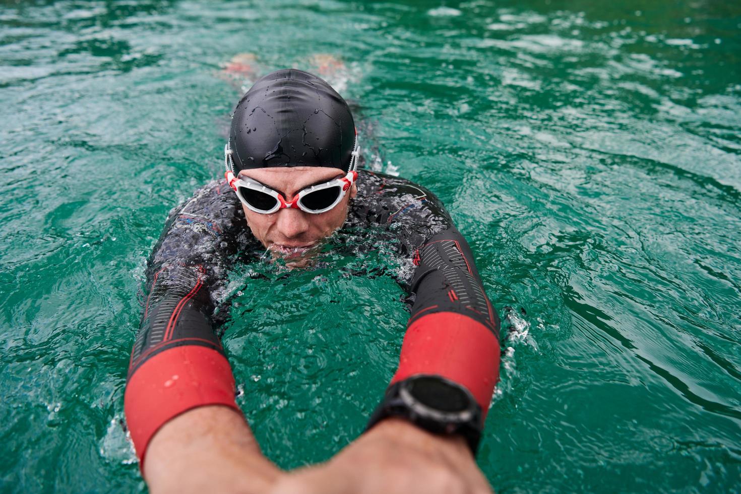 triathlon athlete swimming on lake wearing wetsuit photo