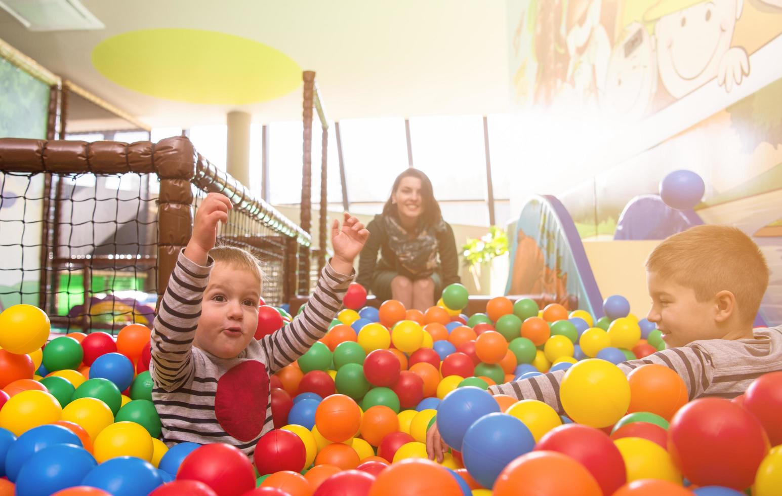 young mom playing with kids in pool with colorful balls photo