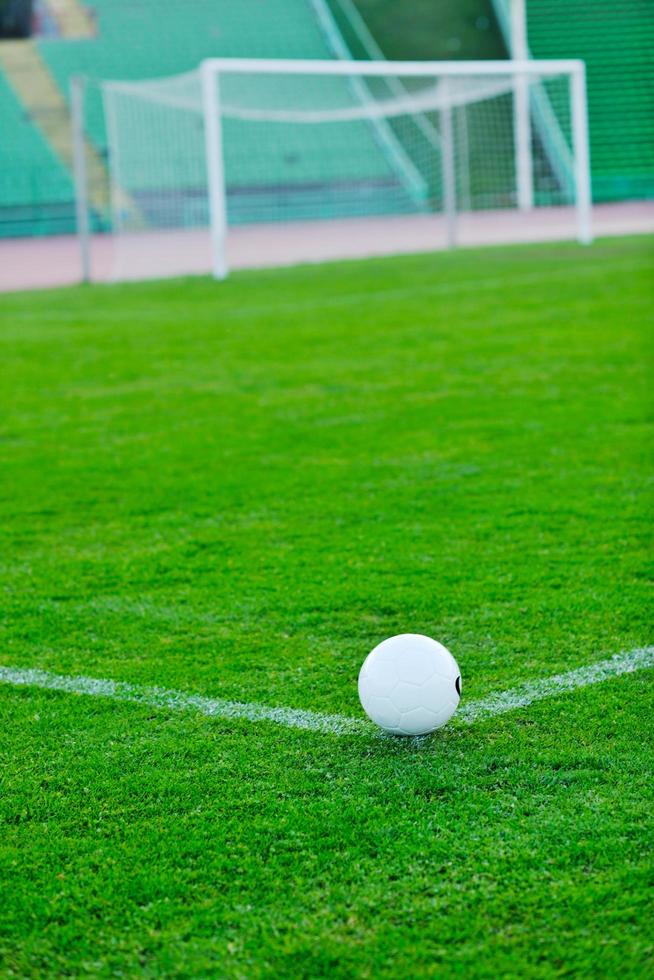 Soccer ball on grass at goal and stadium in background photo