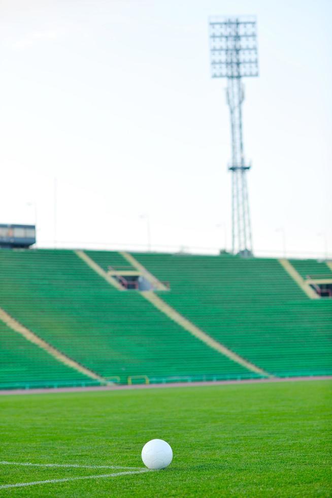 Soccer ball on grass at goal and stadium in background photo