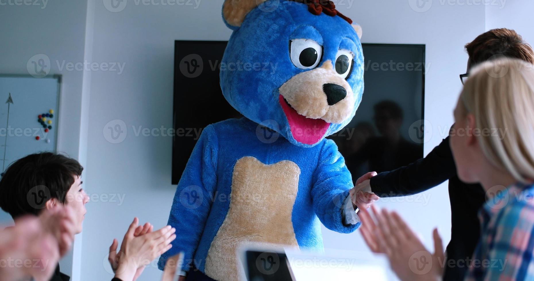 boss dresed as bear having fun with business people in trendy office photo