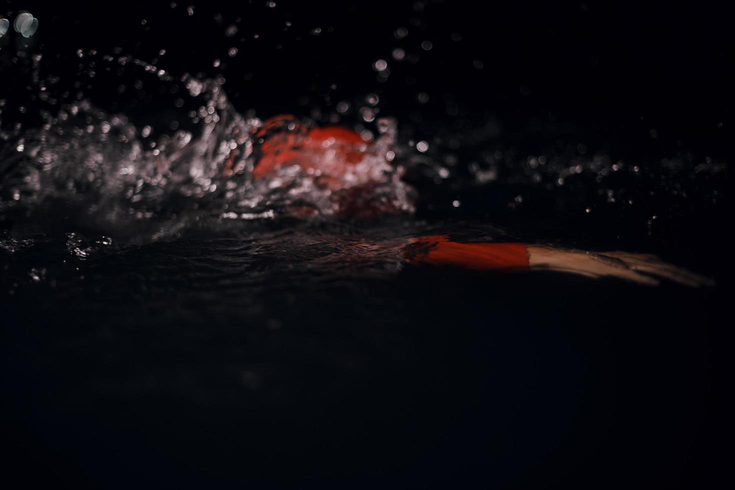 triathlon athlete swimming in dark night  wearing wetsuit photo