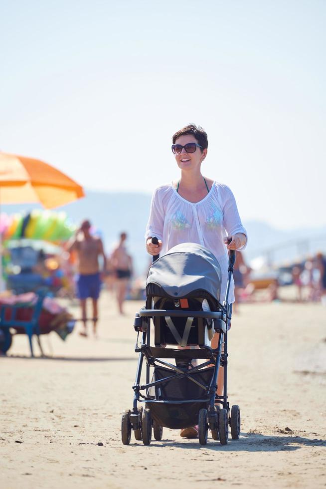 mother walking on beach and push baby carriage photo