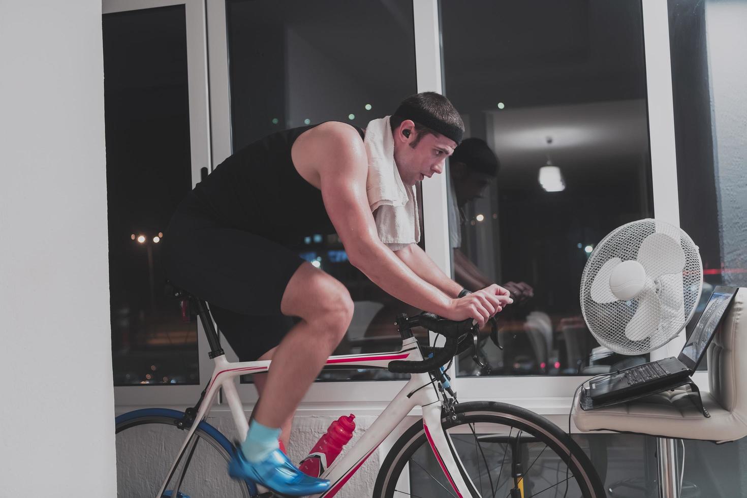 Man cycling on the machine trainer he is exercising in the home at night playing online bike racing game photo