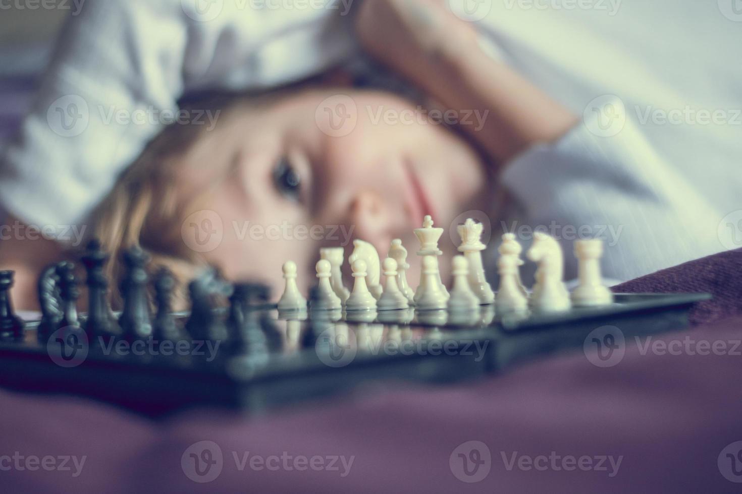 primer plano del tablero de ajedrez con un niño en el fondo. foto