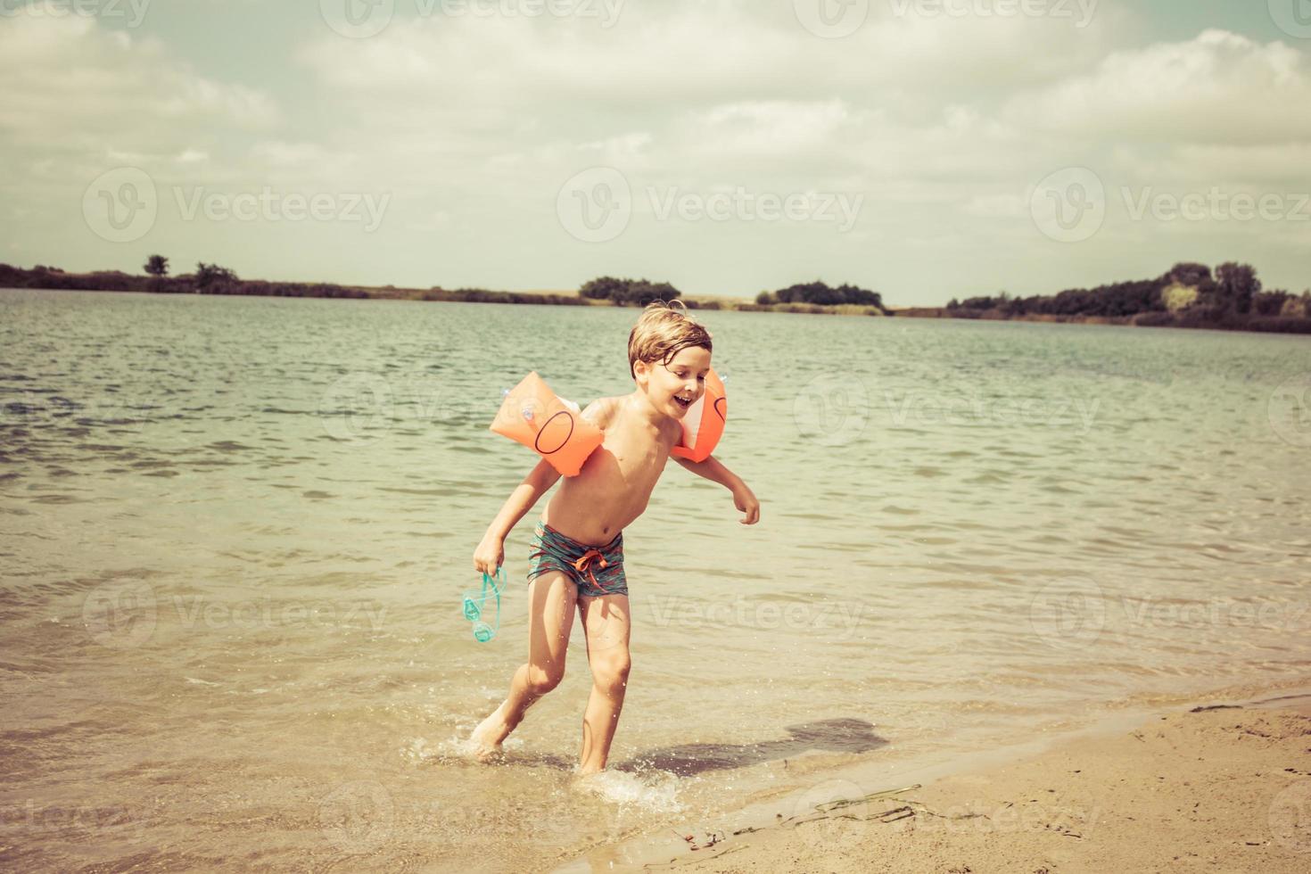 niño feliz divirtiéndose en el día de verano en la playa. foto