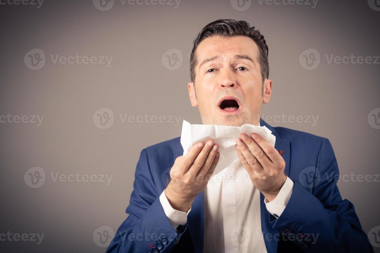 Businessman sneezing in tissue while suffering from allergy. photo