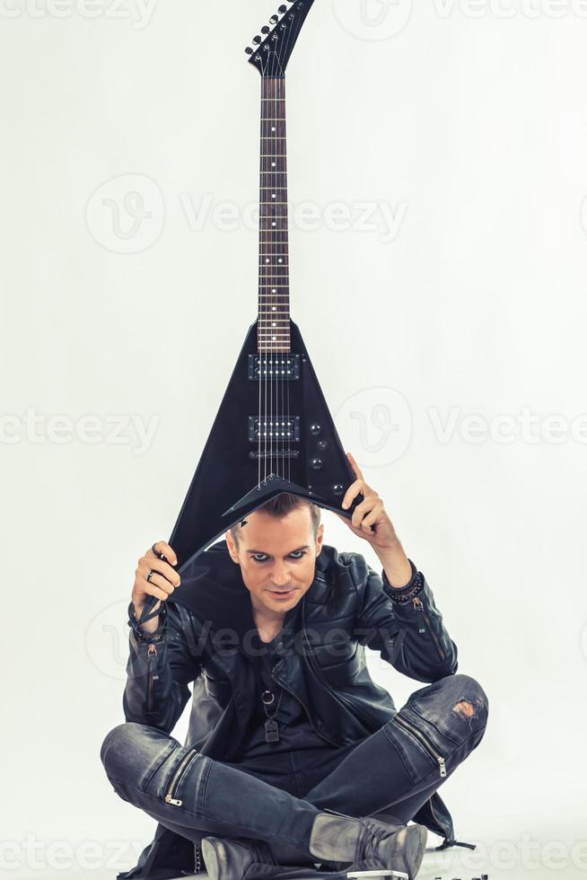 Heavy metal musician holding electric guitar above his head. photo