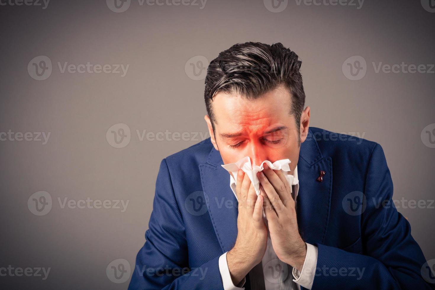 Sick businessman blowing nose in a tissue. photo