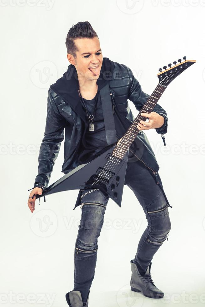 Hard rock musician sticking out tongue while playing electric guitar. photo