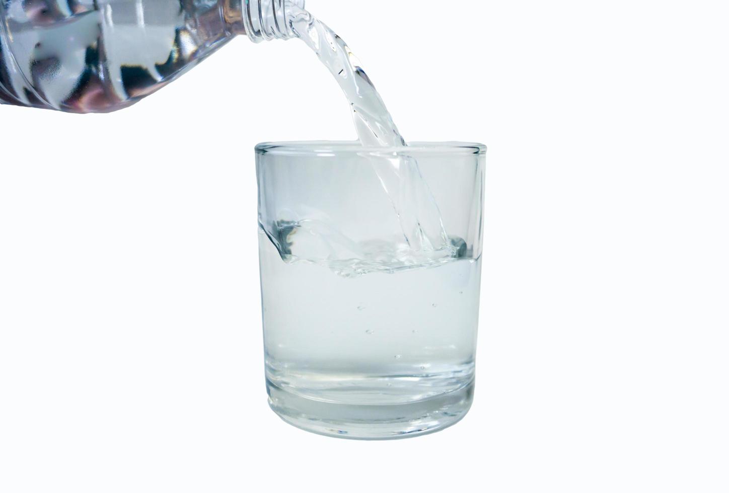 Pouring water into a glass on a white background photo