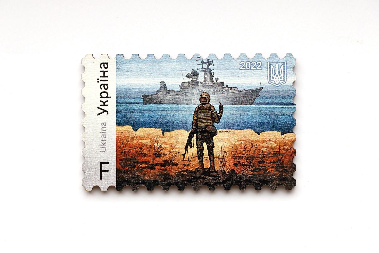 TERNOPIL, UKRAINE - SEPTEMBER 2, 2022 Famous Ukrainian postmark with russian warship and ukrainian soldier as wooden souvenir on white background photo