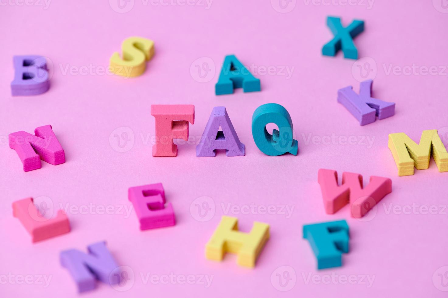 wooden colorful capital letters FAQ on pink background photo