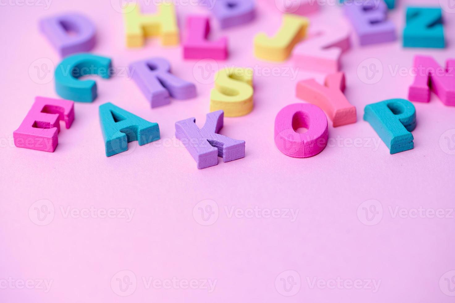 varias letras de madera de colores sobre fondo rosa foto