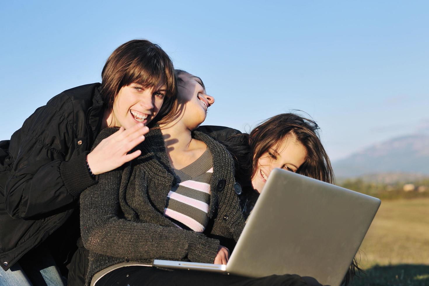 group of teens working on laptop outdoor photo