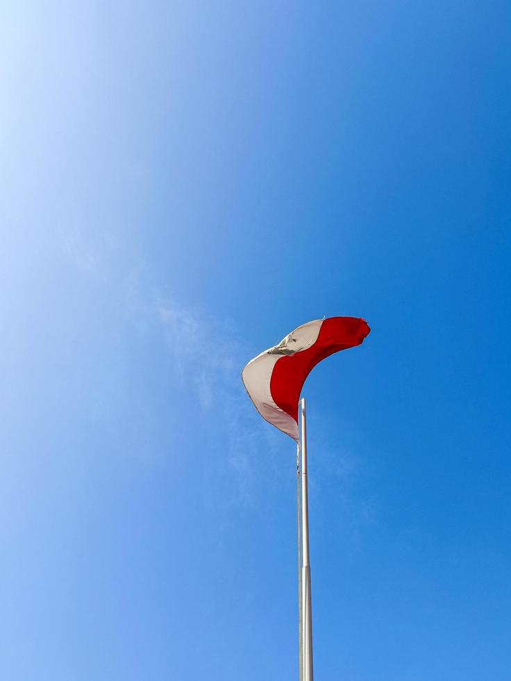 red and white flag flying in the blue sky photo