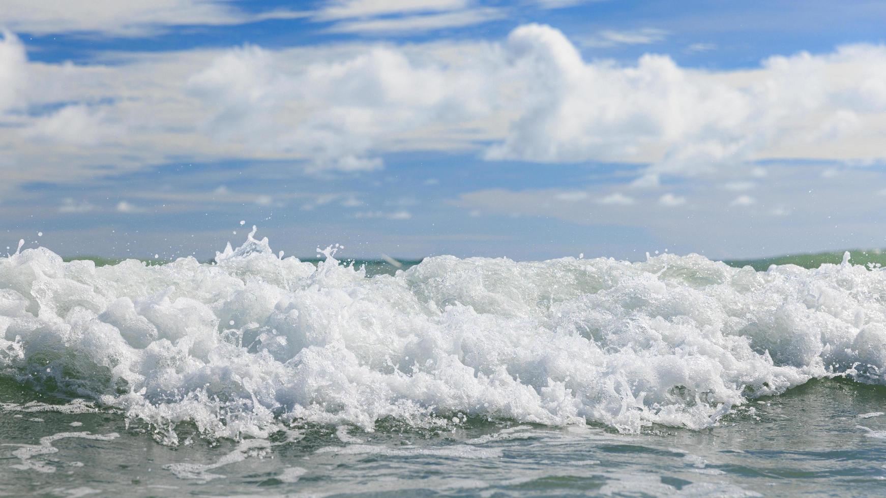 White clean sea waves of tropical beach with blue sky and clouds in colorful sunny day. Scene of summer vacation and holiday business travel concept. Layers of splash water and sky background photo