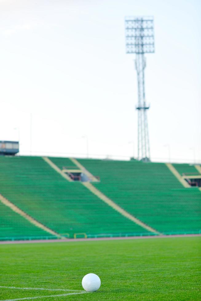 Soccer ball on grass at goal and stadium in background photo