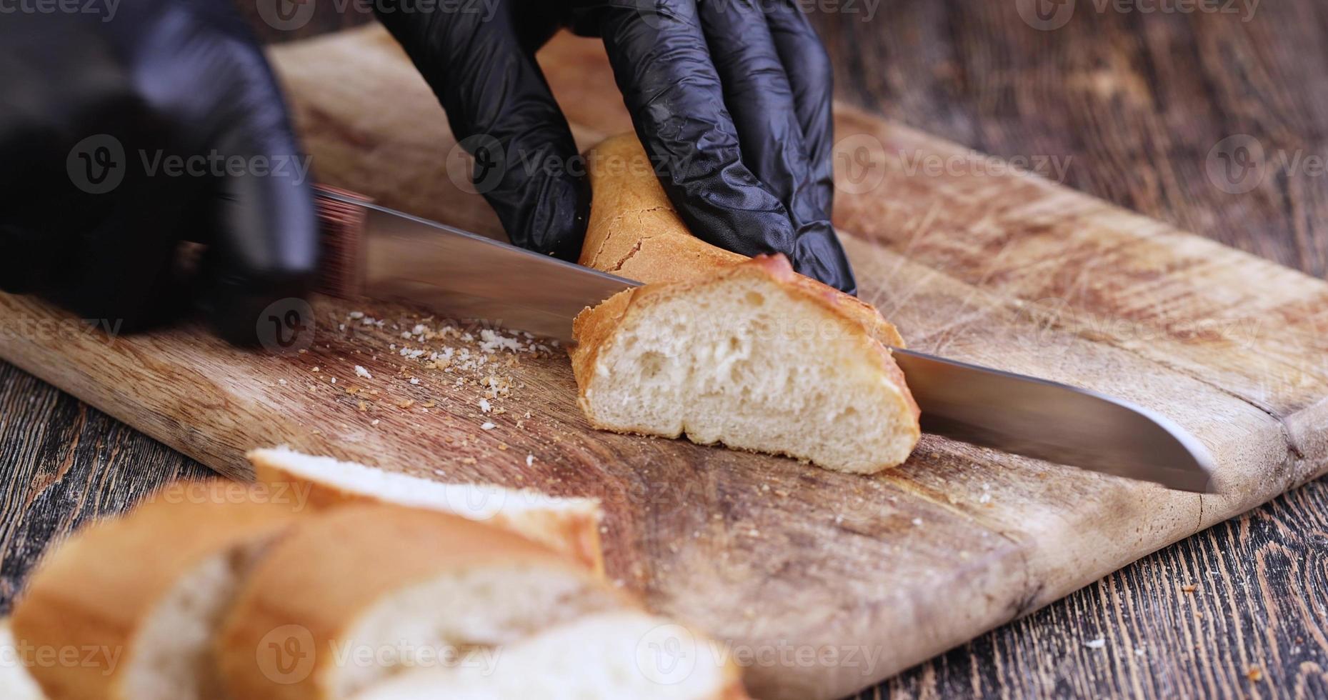 cut a wheat baguette on a cutting board while cooking photo