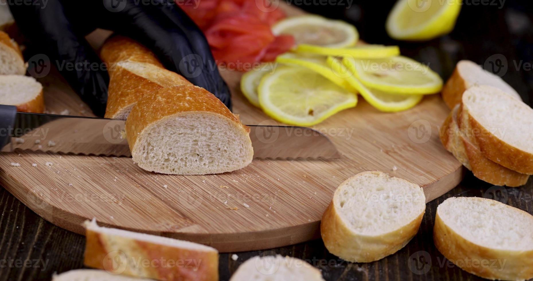 cut fresh wheat baguette into pieces during cooking photo