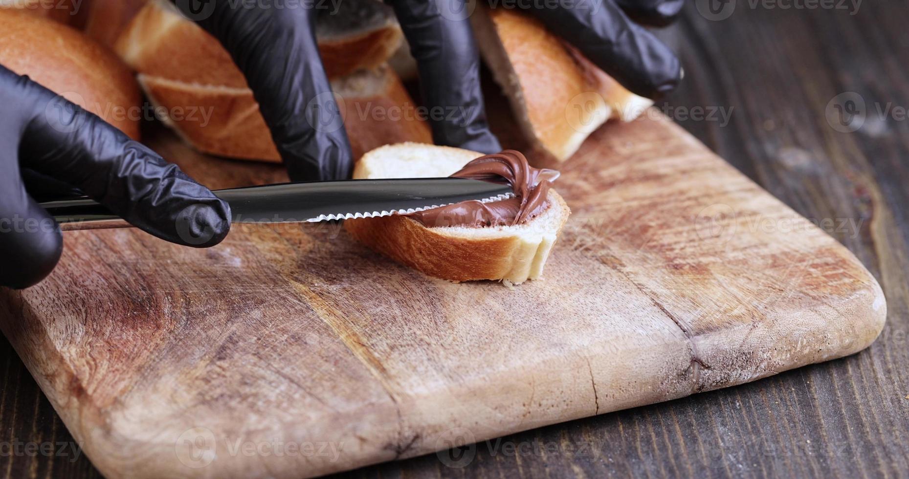 spread chocolate butter on a baguette, close up photo