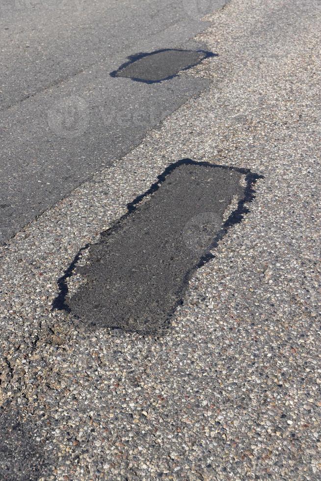 The repaired part of an asphalt road with patches photo