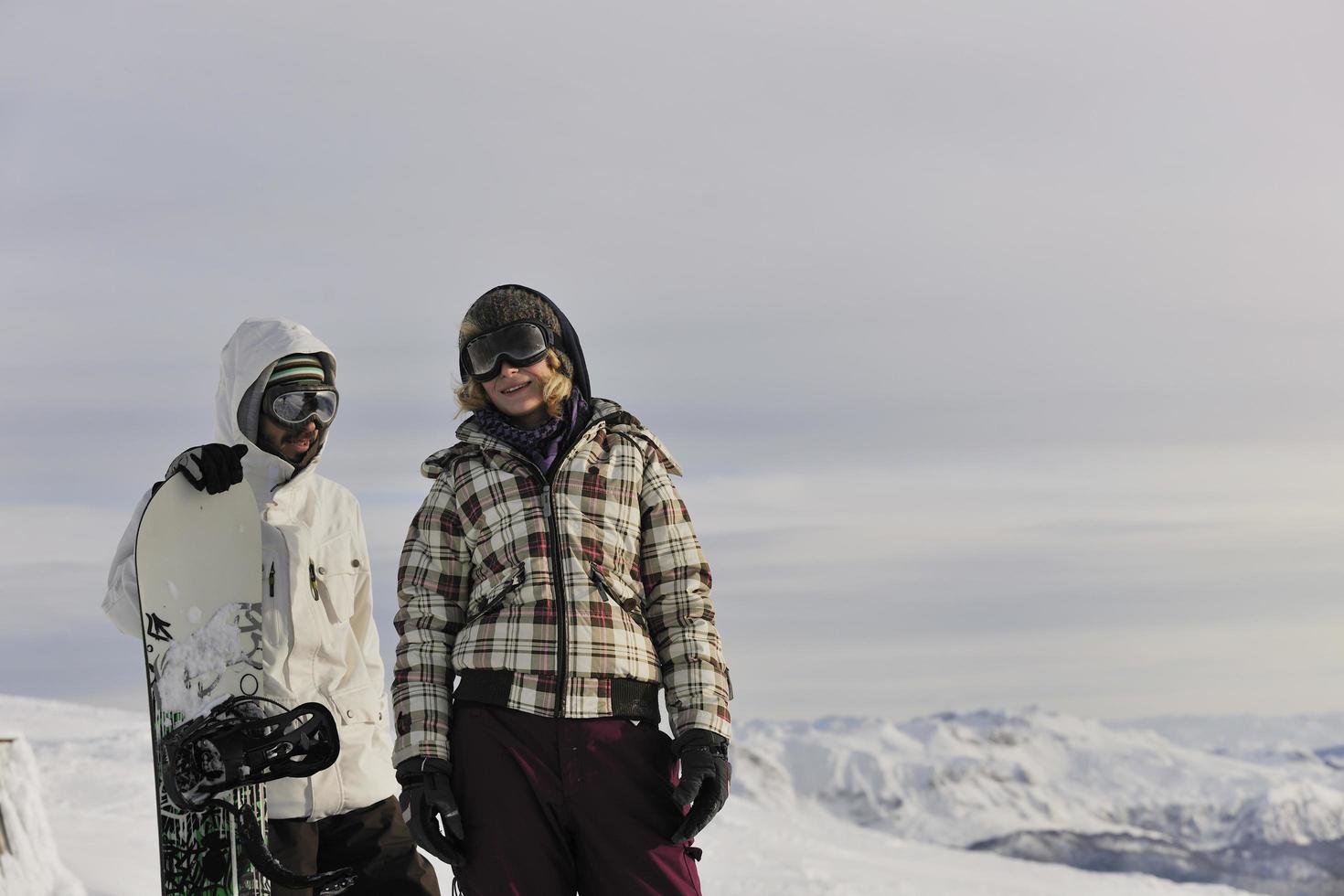 pareja de snowboarders en la cima de la montaña foto