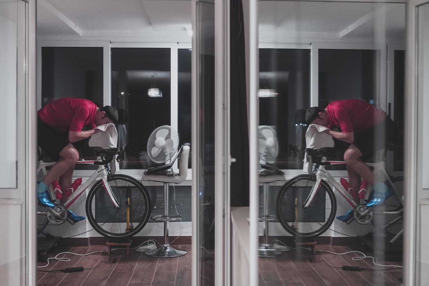 Man cycling on the machine trainer he is exercising in the home at night playing online bike racing game photo