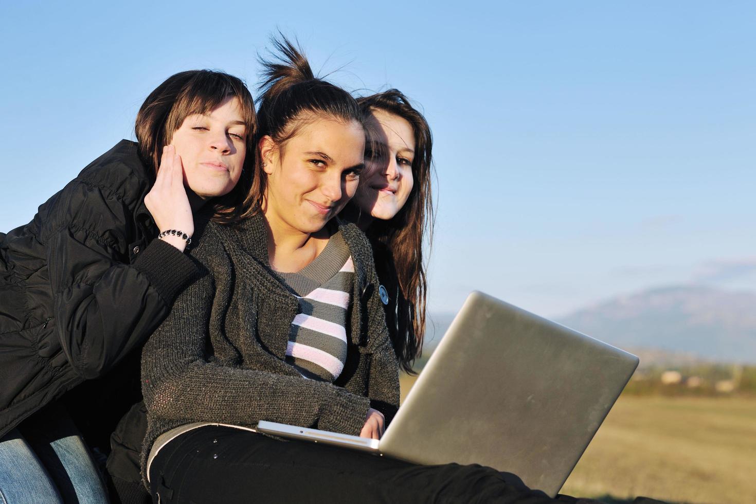 group of teens working on laptop outdoor photo