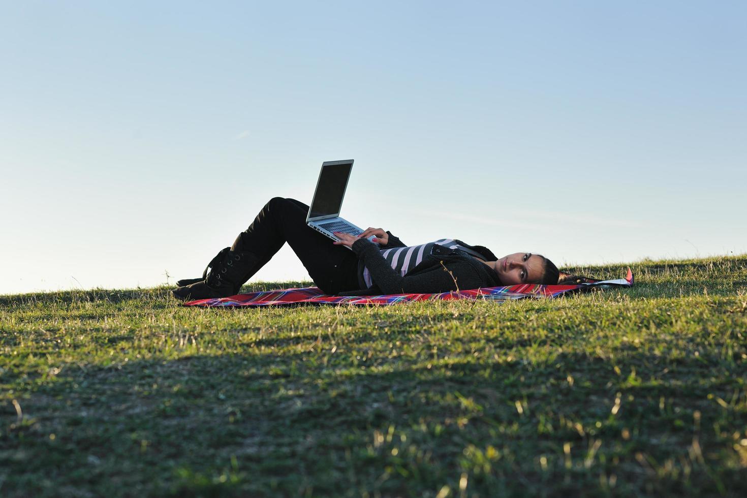 Joven adolescente trabaja en una laptop al aire libre foto