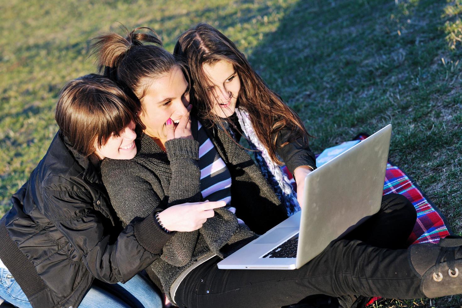 group of teens working on laptop outdoor photo