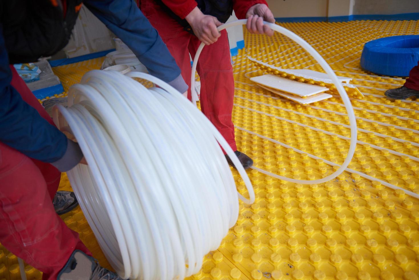 workers installing underfloor heating system photo