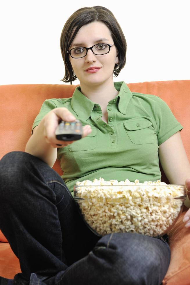 young woman eat popcorn on orange sofa photo