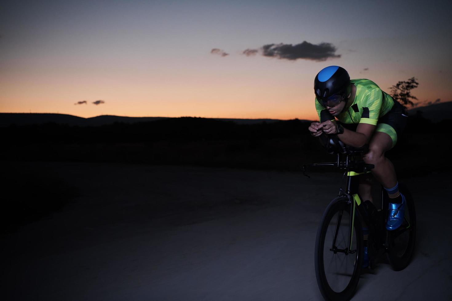 triathlon athlete riding bike fast  at night photo