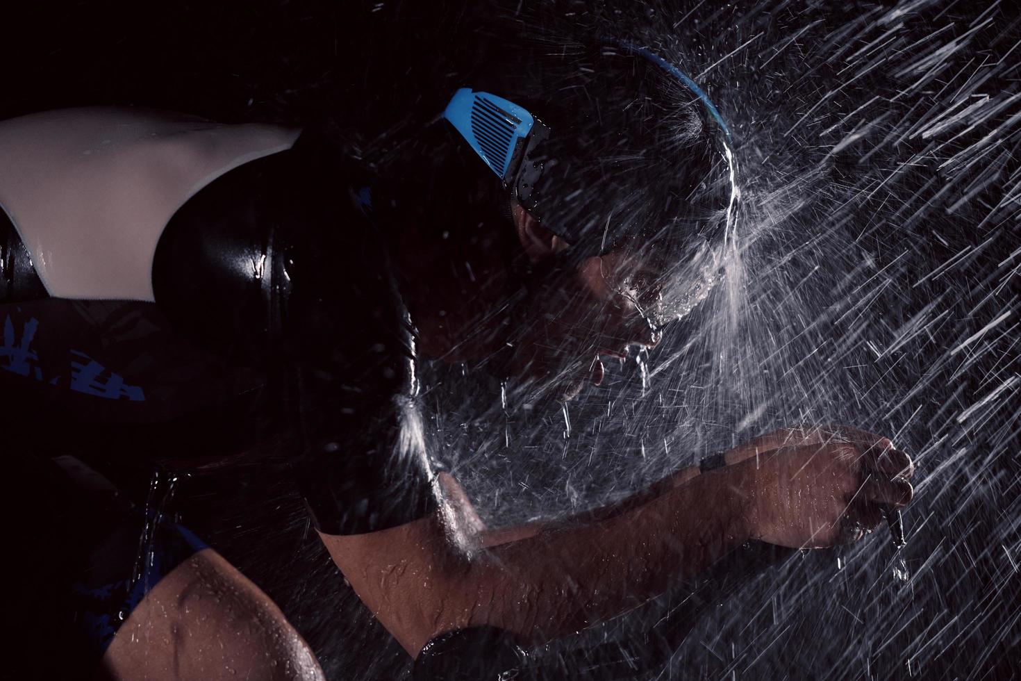 atleta de triatlón montando bicicleta rápido en una noche lluviosa foto