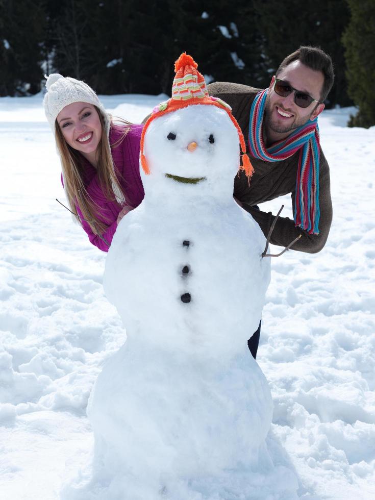 retrato, de, feliz, pareja joven, con, muñeco de nieve foto