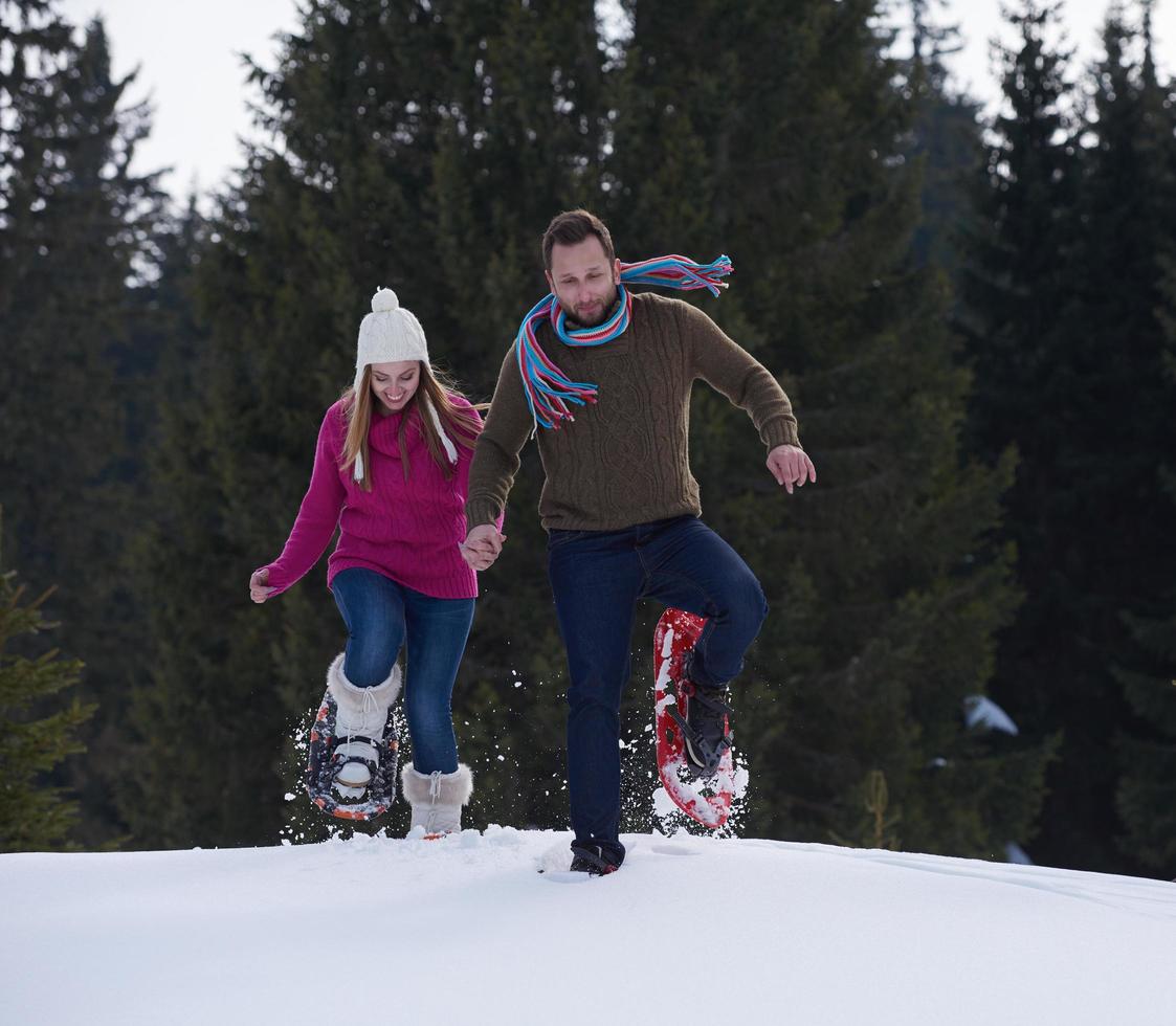 couple having fun and walking in snow shoes photo