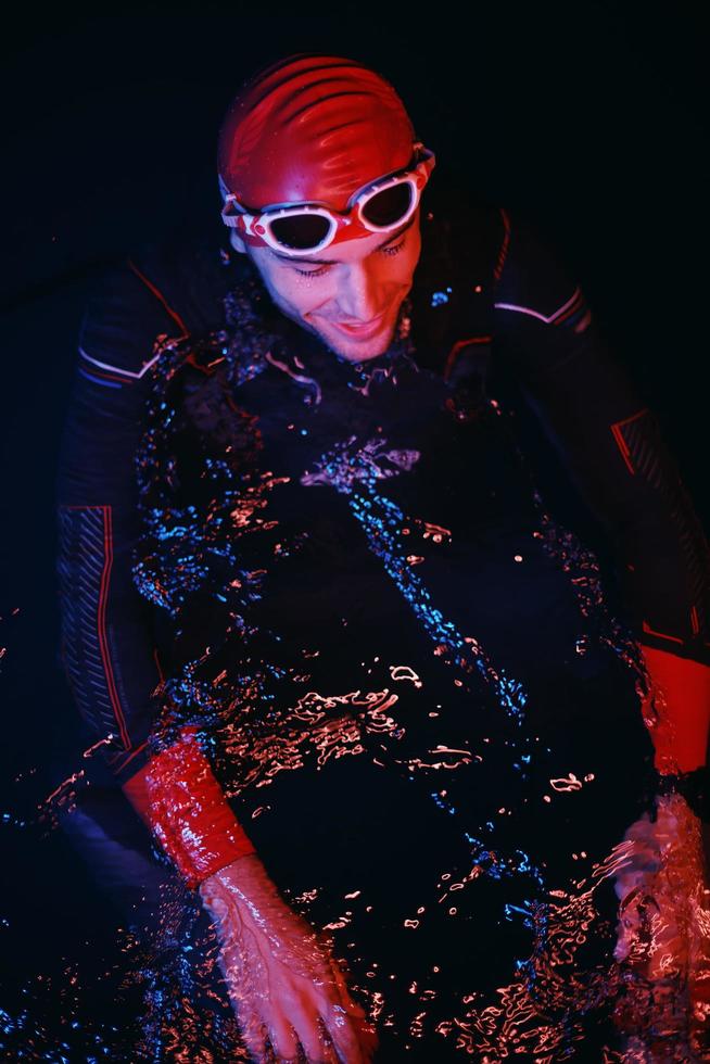 authentic triathlete swimmer having a break during hard training on night neon gel light photo