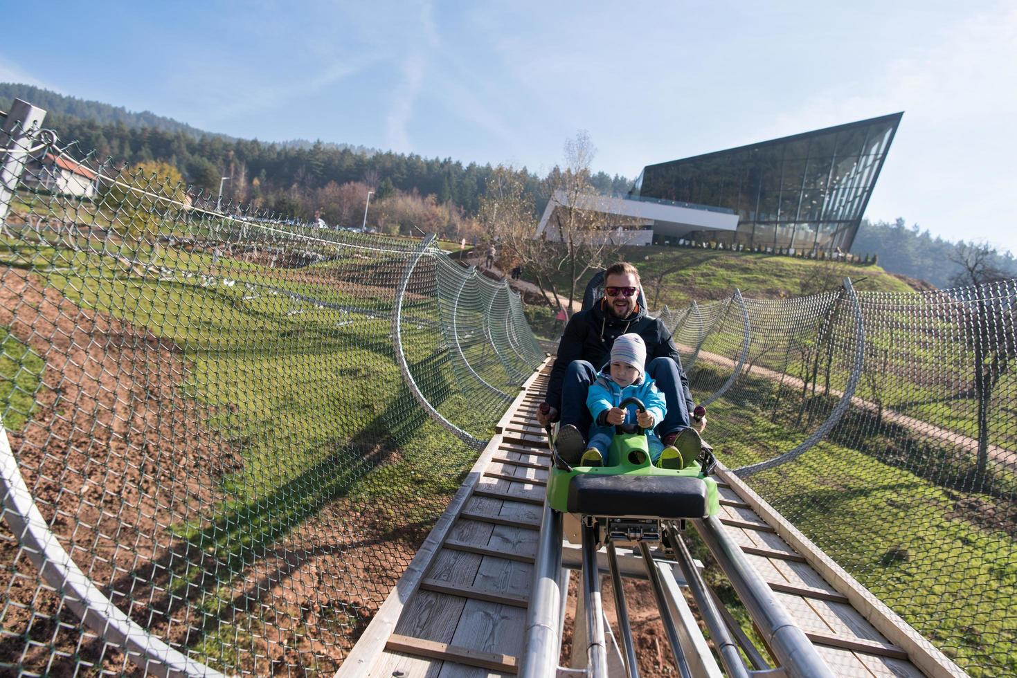 father and son enjoys driving on alpine coaster photo