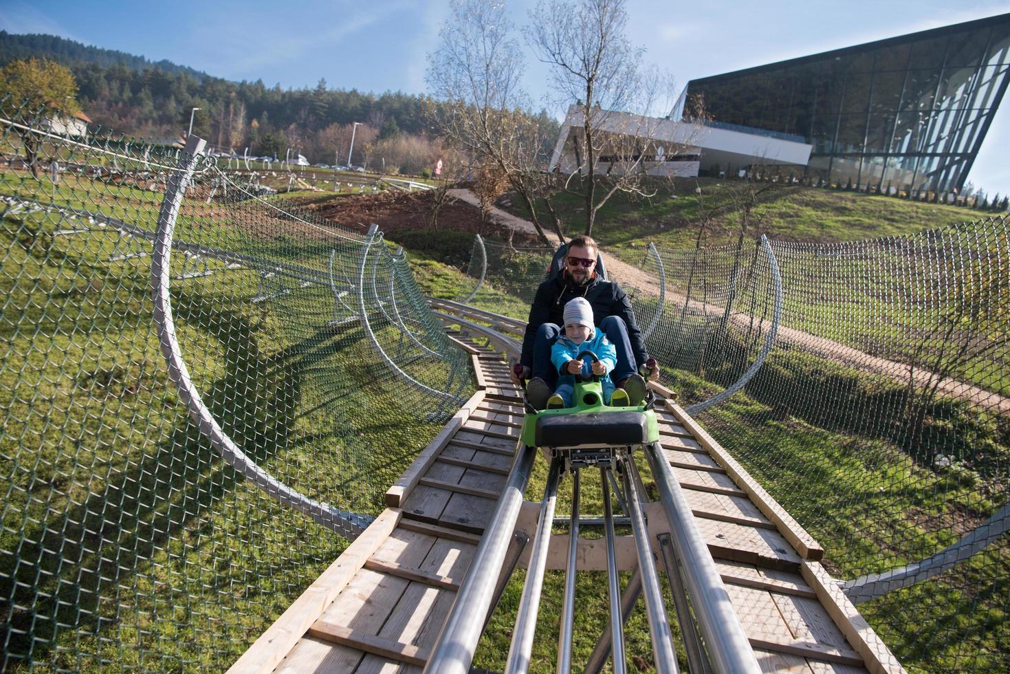 father and son enjoys driving on alpine coaster photo