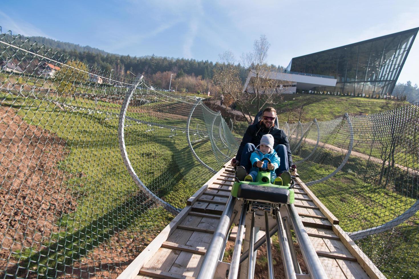 padre e hijo disfrutan conduciendo en montaña rusa alpina foto