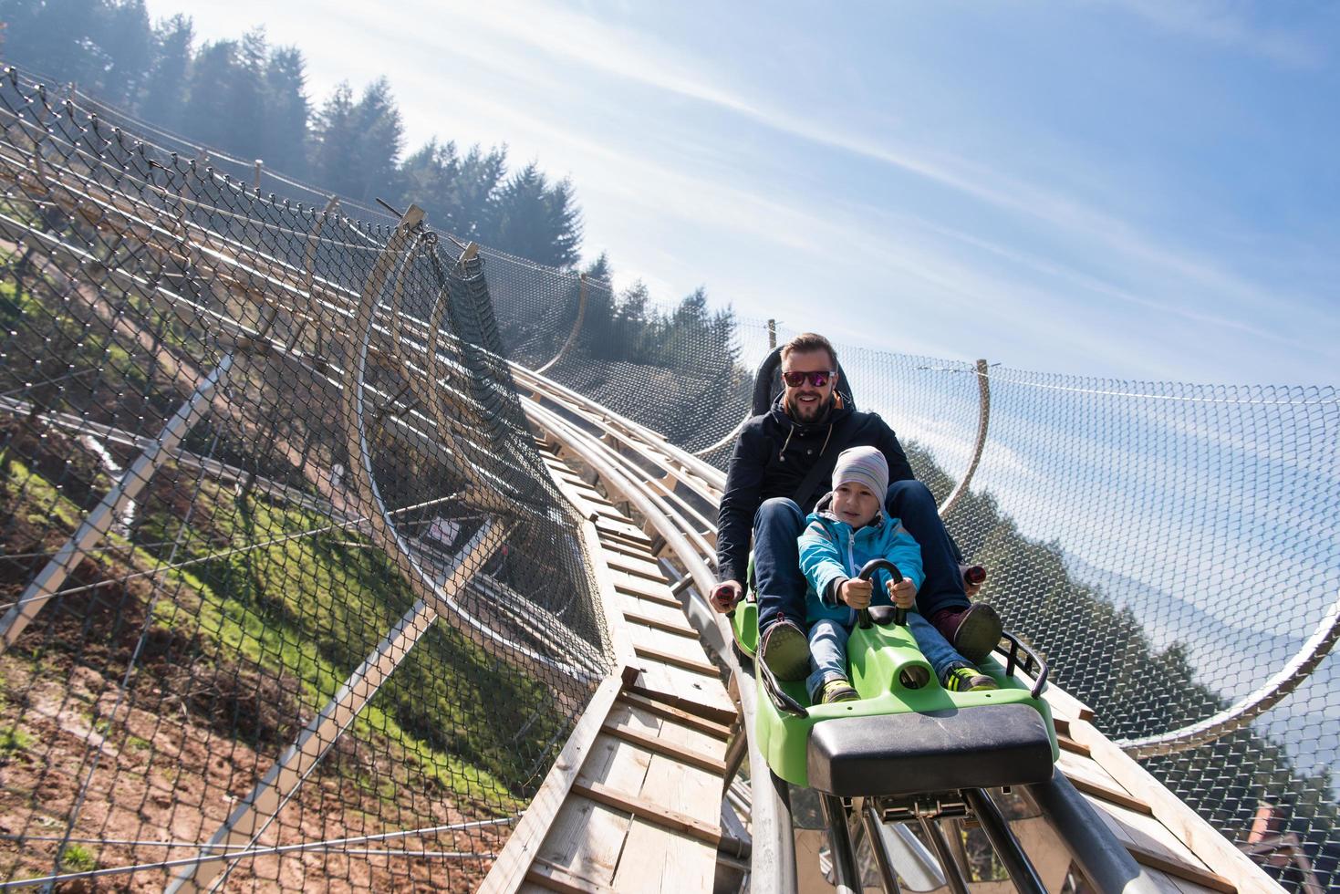 father and son enjoys driving on alpine coaster photo